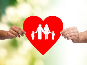 closeup of hands holding red heart with family