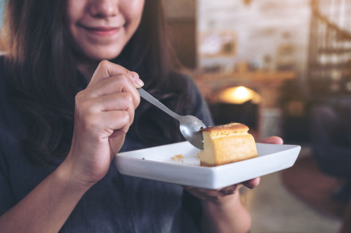 Closeup image of a happy woman holding and enjoy eating cheese c