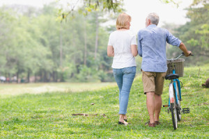 96079146 - senior couple walking their bike along happily talking happily.